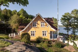 Hus ved vannet malt med JOTUN DRYGOLIN Nordic Extreme i fargene Skagengul Bomull Skyggebrun